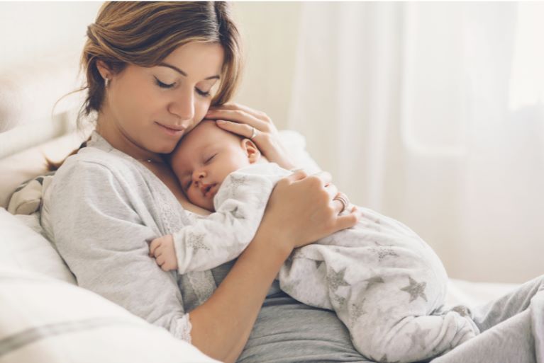 Une jeune maman avec son bébé contre elle car son bébé ne dort que dans ses bras la nuit