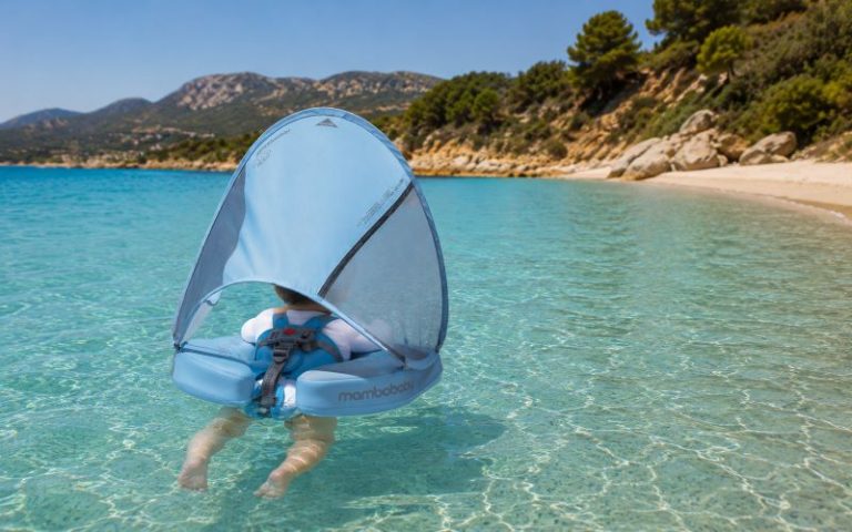 Plage avec bébé en Corse avec bouée anti-UV flottant dans une eau turquoise cristalline.