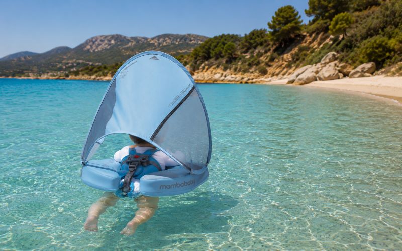 Plage avec bébé en Corse avec bouée anti-UV flottant dans une eau turquoise cristalline.