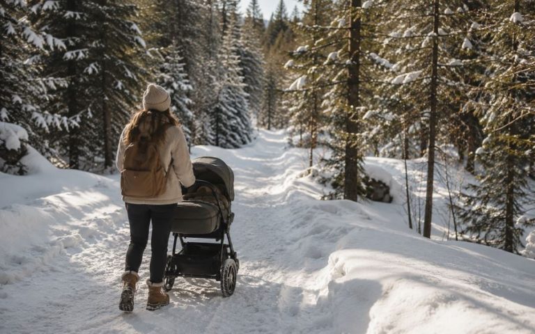 Comment habiller bébé au ski : parent promenant une poussette tout-terrain sur un chemin enneigé au milieu des sapins en montagne.