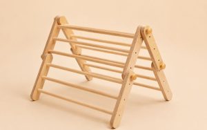 Jouet Montessori triangle de Pikler en bois naturel pour développer la motricité, l'équilibre et l'autonomie des jeunes enfants.