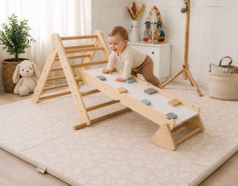 Motricité libre bébé : enfant explorant un triangle de Pikler sur un grand tapis de motricité rembourré dans un espace sécurisé et adapté à son développement moteur.