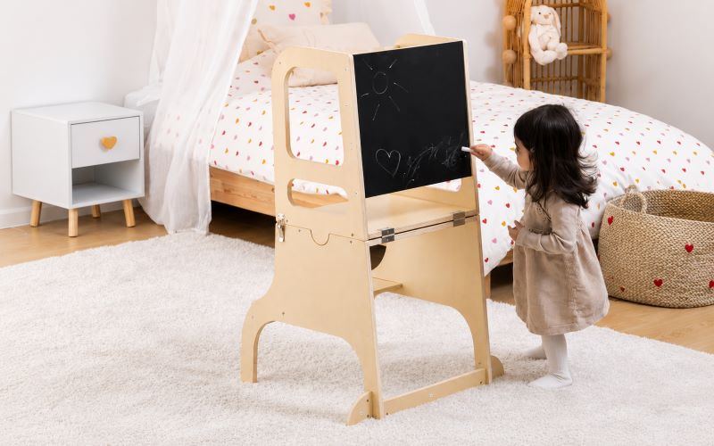 Tour d'observation enfant en bois utilisée par une petite fille dans sa chambre pour dessiner et développer son autonomie au quotidien