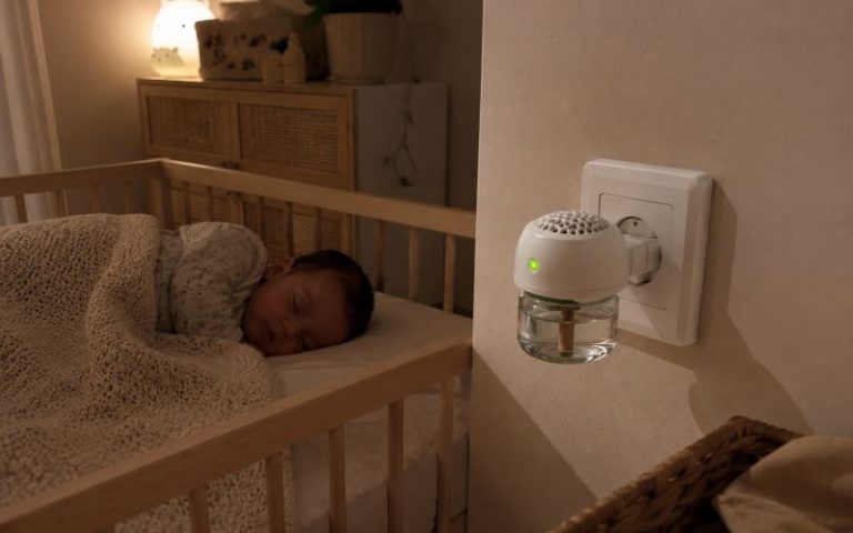 Prise anti moustique bébé branchée près du lit d’un nourrisson endormi dans une chambre aux tons beige et bois.
