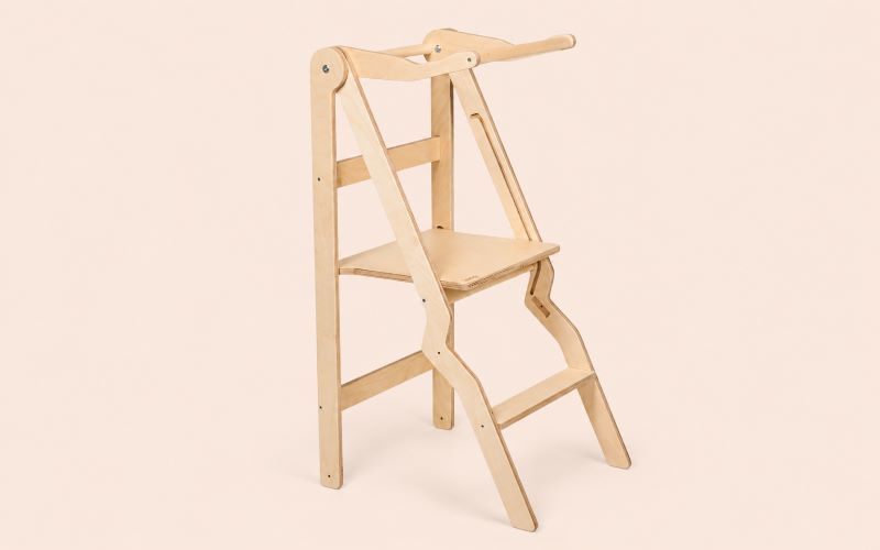 Tour d'observation pliable en bois clair sur fond beige rosé